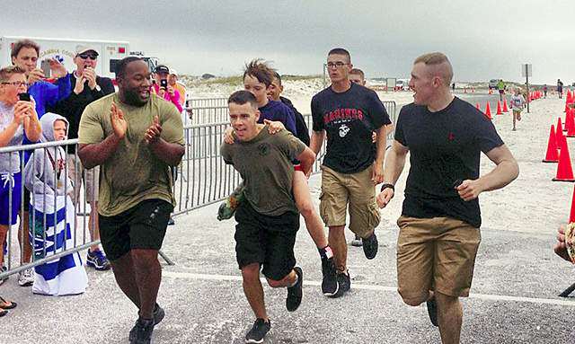 Marine carrying triathlete across the finish line