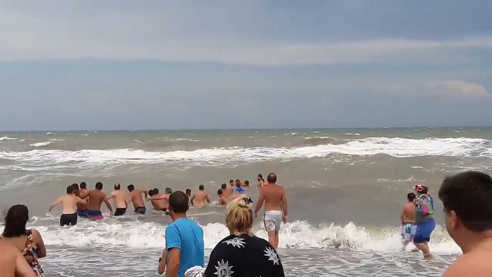 Beachgoes form a human chain to rescue struggling swimmers